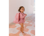 Bambina al mare con zaino anti sabbia Monnëka Pink Whale sulle spalle