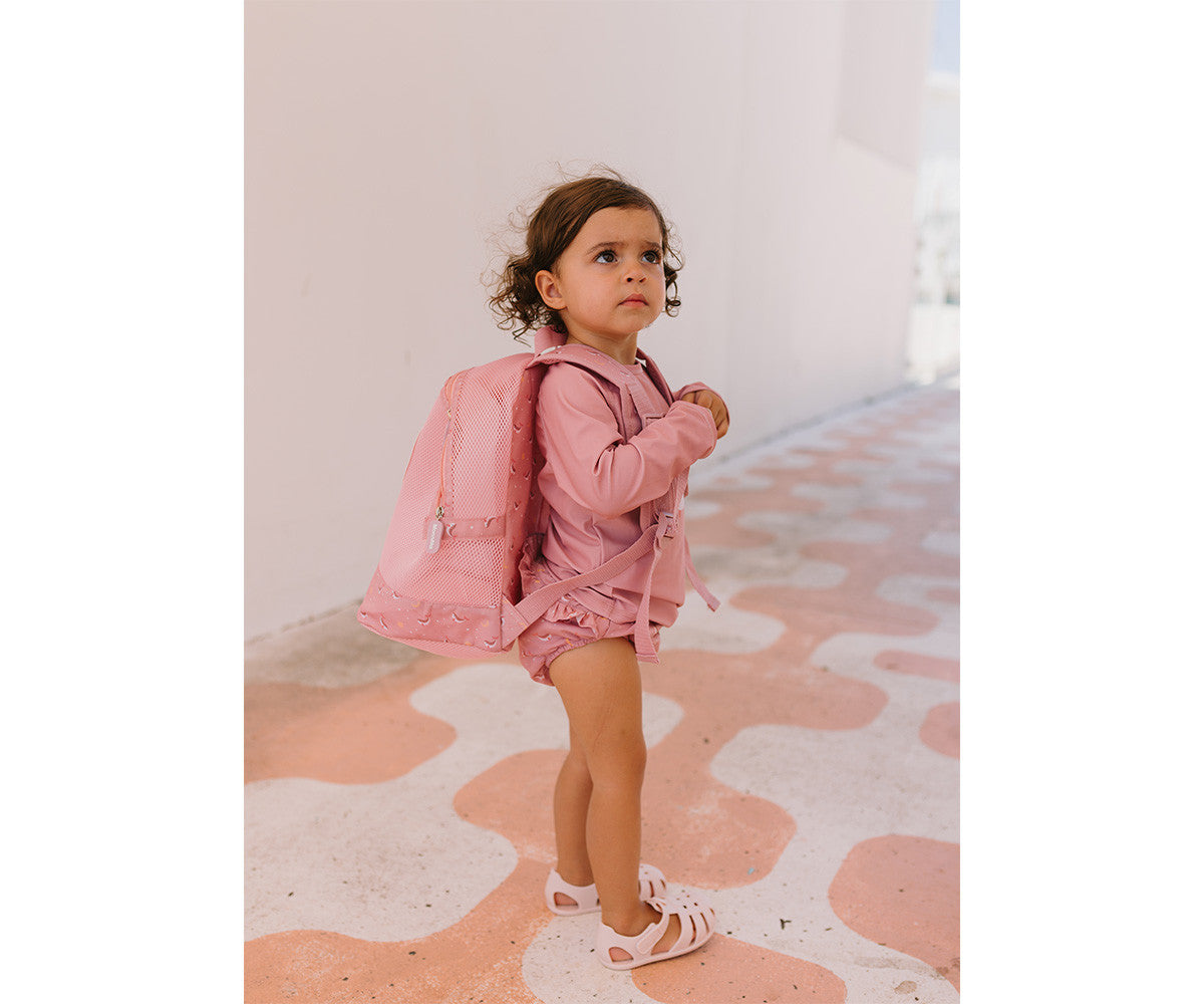 Bambina al mare con zaino anti sabbia Monnëka Pink Whale sulle spalle