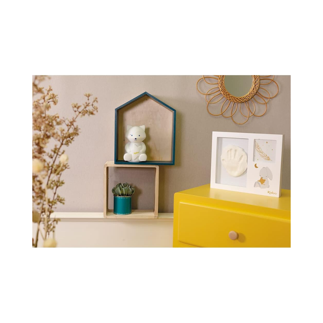 Cornice Kaloo con impronta e foto del bambino, posizionata su un mobile in una cameretta dal design delicato