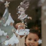 Bambina posiziona adesivi natalizi di Little Dutch  un albero di Natale, fiocchi di neve e figure festose.