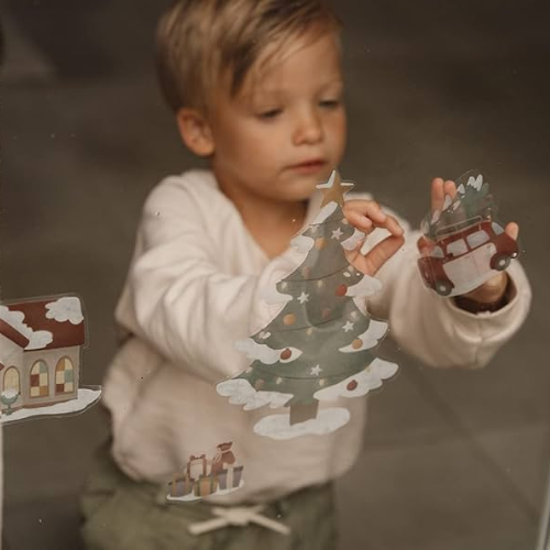 Bambino posiziona adesivi natalizi di Little Dutch su una finestra
