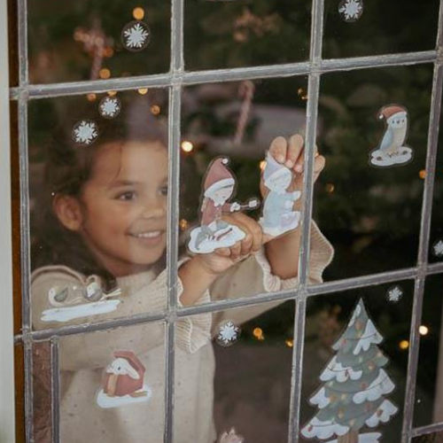 Bambina posiziona adesivi natalizi di Little Dutch su una finestra