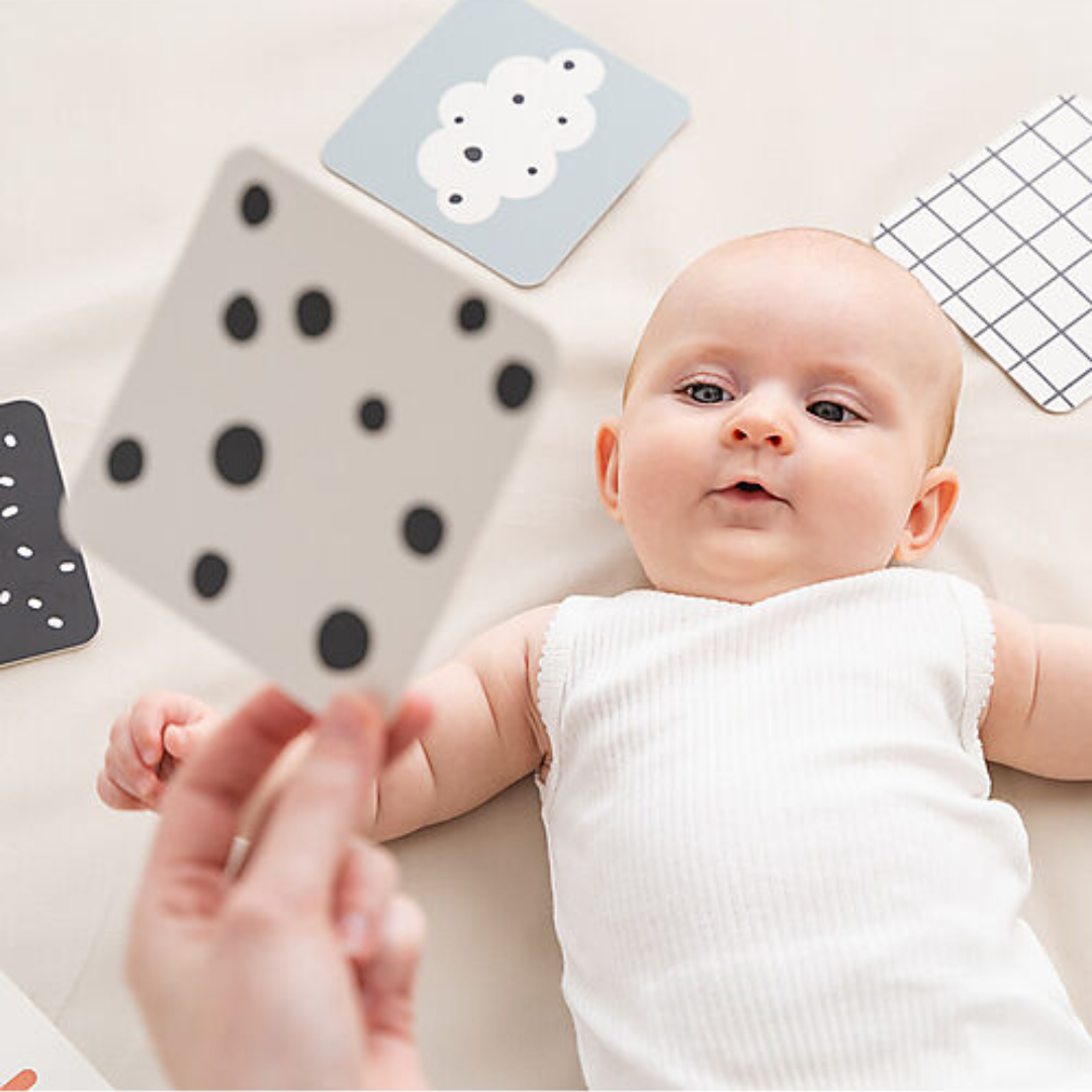 Neonato interagisce con una carta bianco e nero Done By Deer durante il tummy time.