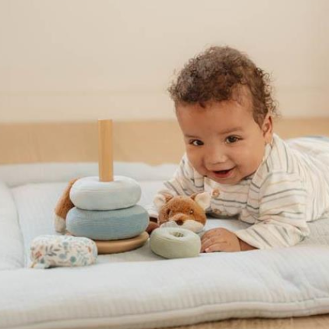 Bambino che gioca con il Rocking Ring Stacker di Little Dutch, sorridendo mentre impila gli anelli morbidi.