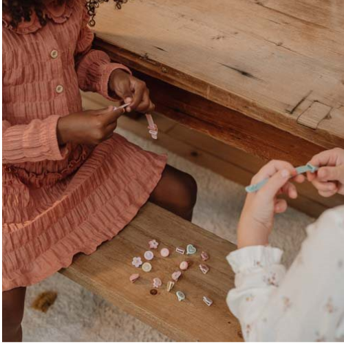 Due bambine sedute che mostrano i loro braccialetti personalizzati, realizzati con il kit braccialetti bambina Fairy Garden di Little Dutch.