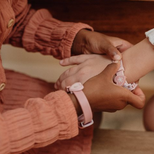 Due bambine che indossano braccialetti creati con il set perline per braccialetti di Little Dutch, con dettagli floreali e colori pastello.