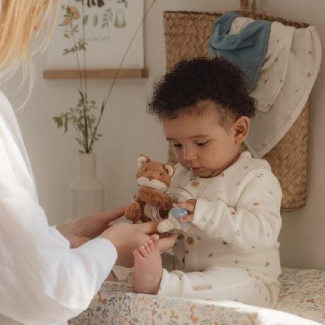 Bambino che gioca con il pupazzo doudou Little Dutch Volpe, un gioco sensoriale ideale per coordinazione visiva e uditiva.