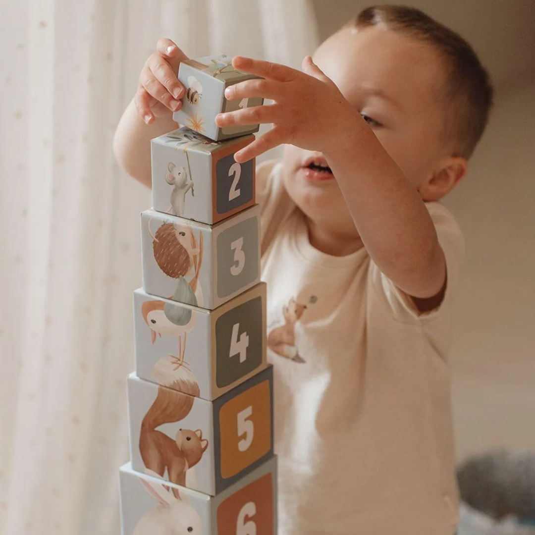 Bambino di 18 mesi che allena la motricità fine impilando i cubi educativi Little Dutch.